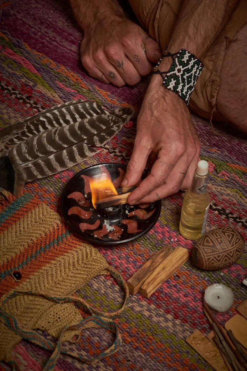Practitioner lighting a palo santo stick in a ceramic burner during an Andean cleansing ritual